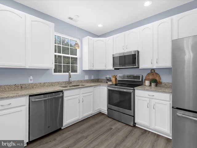 a kitchen with granite countertop white cabinets and white appliances