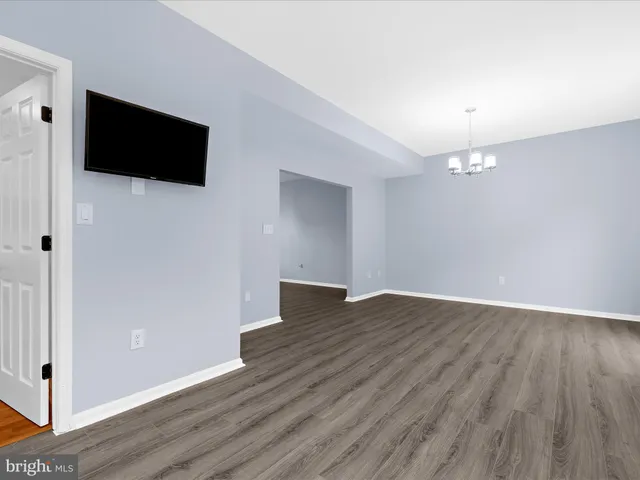 a view of an empty room with wooden floor and a flat screen tv