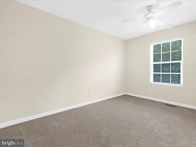 an empty room with a window and a ceiling fan
