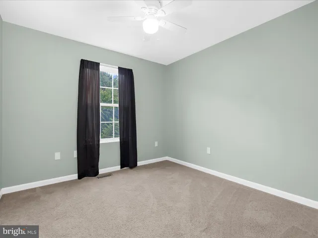 an empty room with a ceiling fan and a window