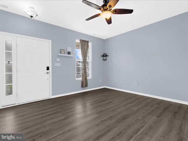 an empty room with wooden floor closet and windows