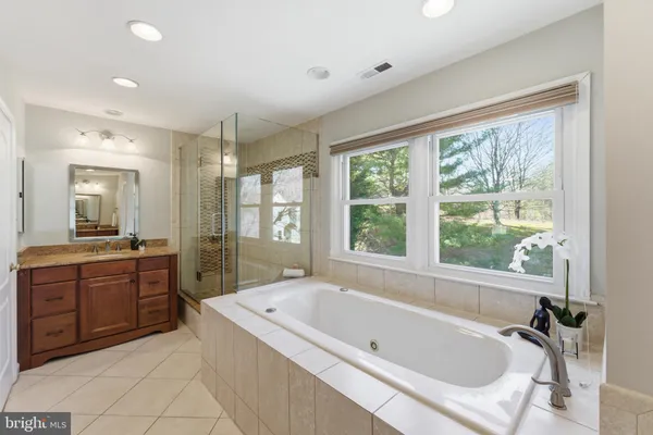 a spacious bathroom with a tub a sink and mirror