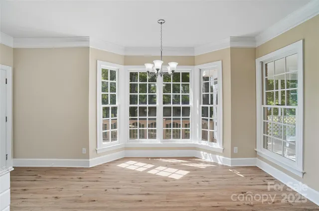 a view of an empty room with wooden floor and windows