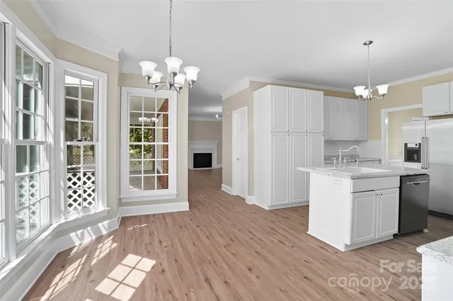 a kitchen that has a lot of white cabinets and stainless steel appliances