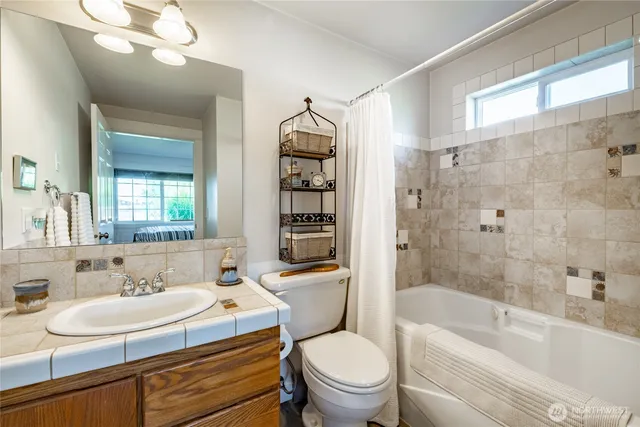 a bathroom with a granite countertop sink a toilet a mirror a bathtub and shower