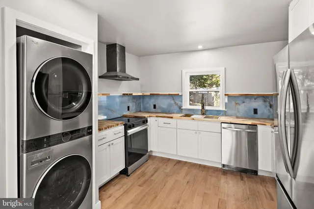 a kitchen with stainless steel appliances granite countertop a stove a sink a refrigerator and wooden floors