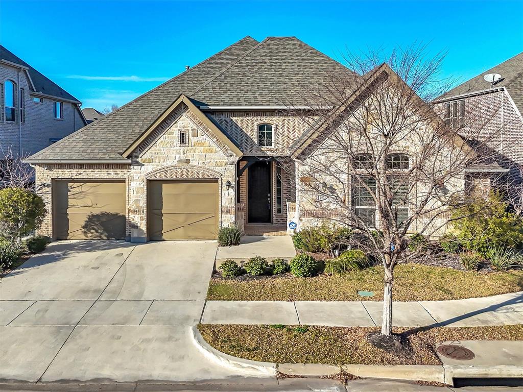 French provincial home with stone siding, roof with shingles, driveway, a garage, and brick siding