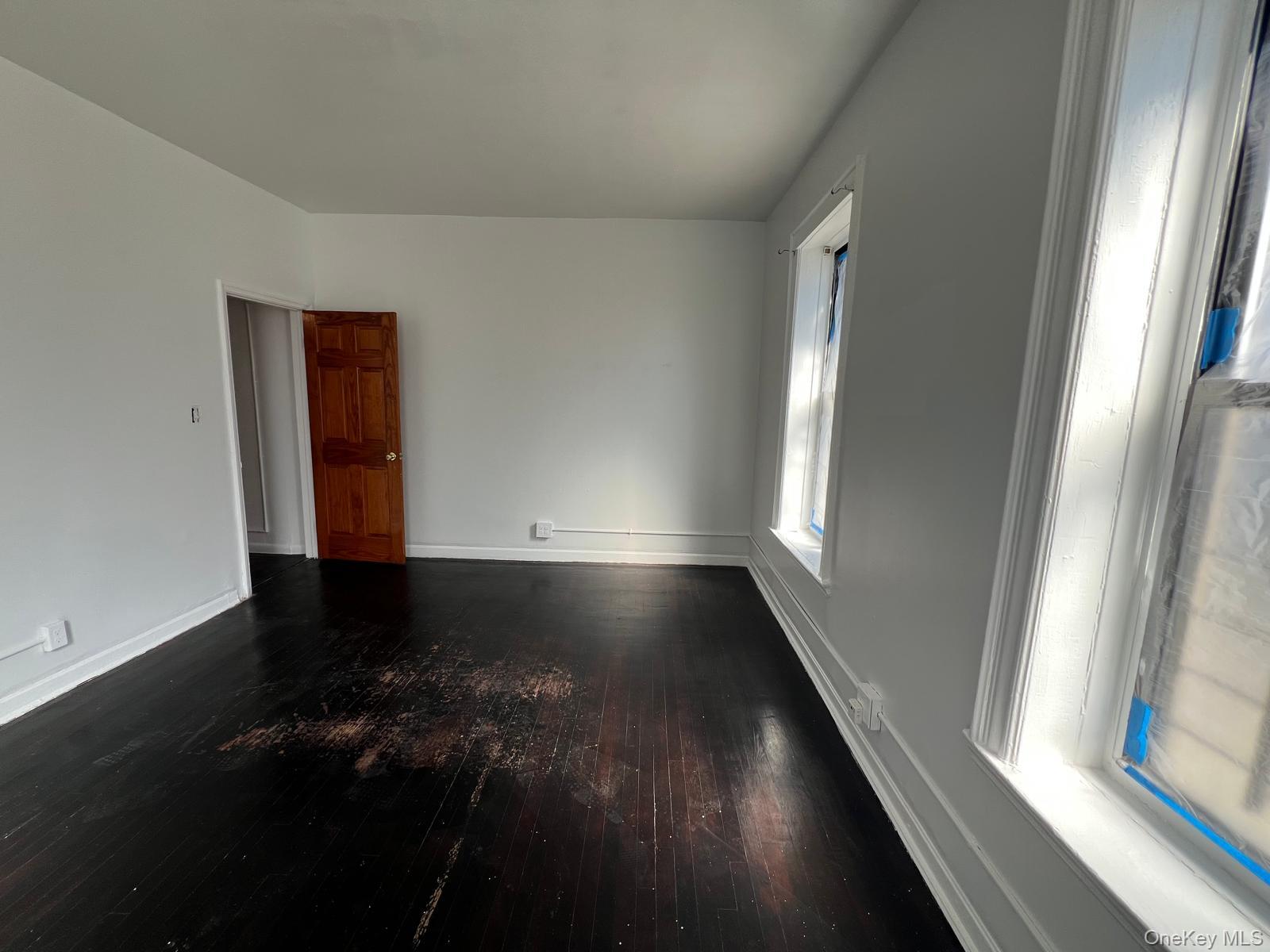 97-52 75th Street, Unit B1 Queens, NY 11416 - Photo 13 of 19 Empty room with dark wood finished floors and baseboards