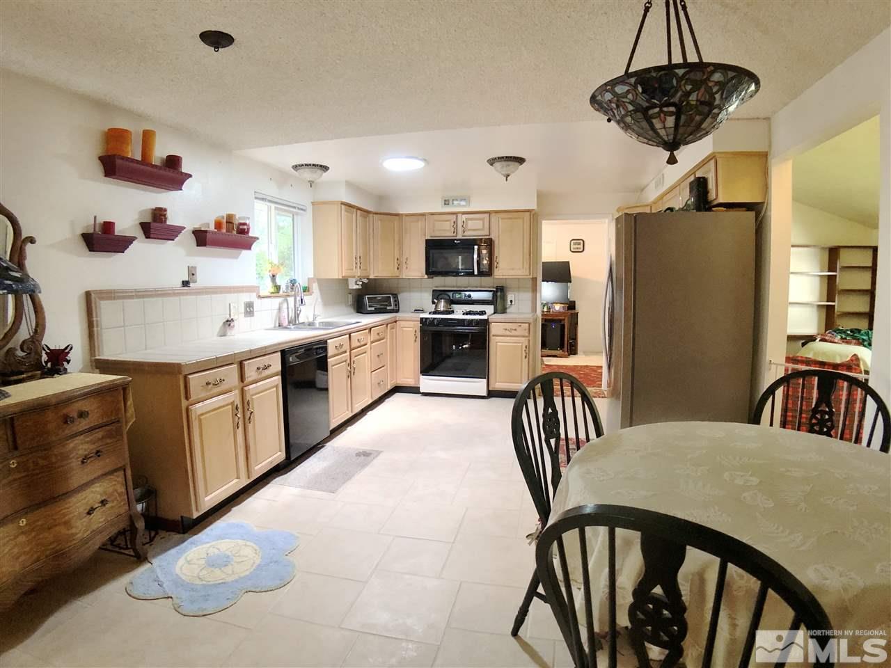 4210 Billy Drive Reno, NV 89502 - Photo 24 of 31 a kitchen with stainless steel appliances granite countertop a stove a sink dishwasher a dining table and chairs with wooden floor