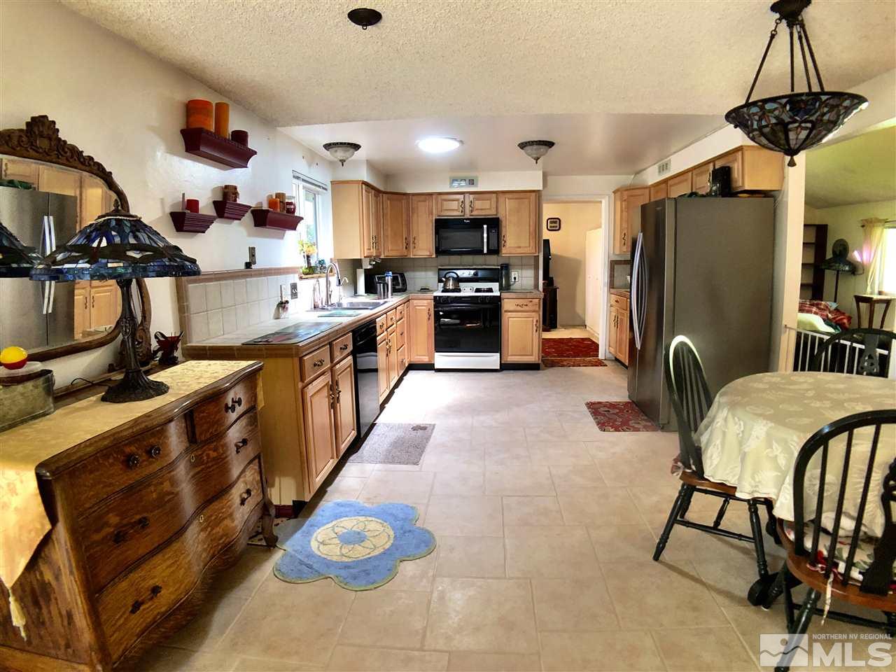 4210 Billy Drive Reno, NV 89502 - Photo 9 of 31 a kitchen with stainless steel appliances kitchen island granite countertop a table chairs in it and wooden floors