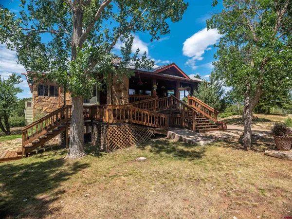 a view of a wooden house with a large tree and wooden fence