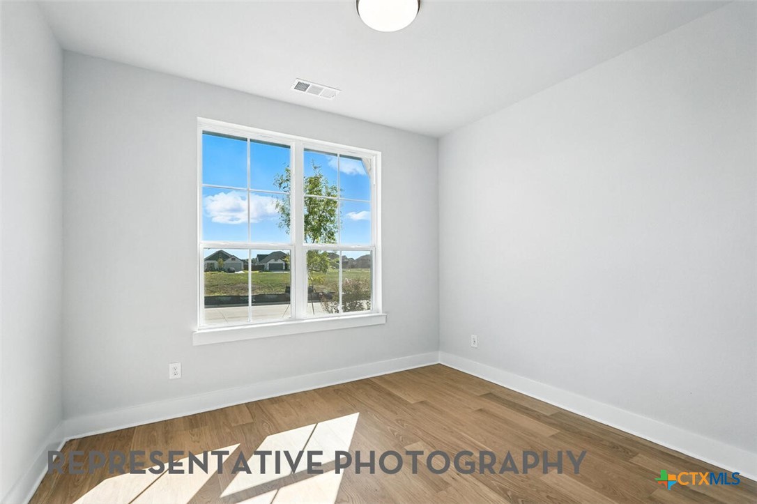 8905 Turaco Trail Austin, TX 78744 - Photo 15 of 27 an empty room with wooden floor and windows