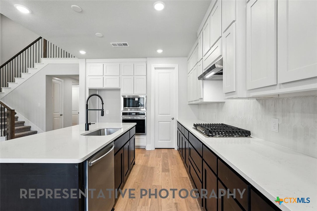 8905 Turaco Trail Austin, TX 78744 - Photo 5 of 27 a kitchen with kitchen island a sink stove and cabinets