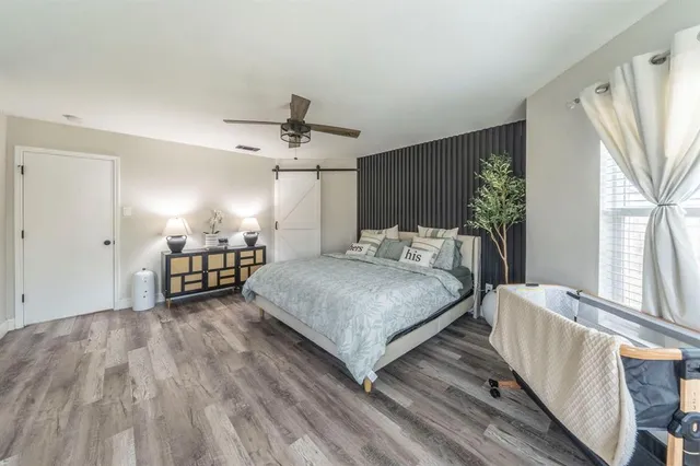 a bedroom with a large bed couch and windows