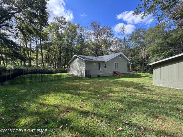 a view of a house with a small yard and a large tree