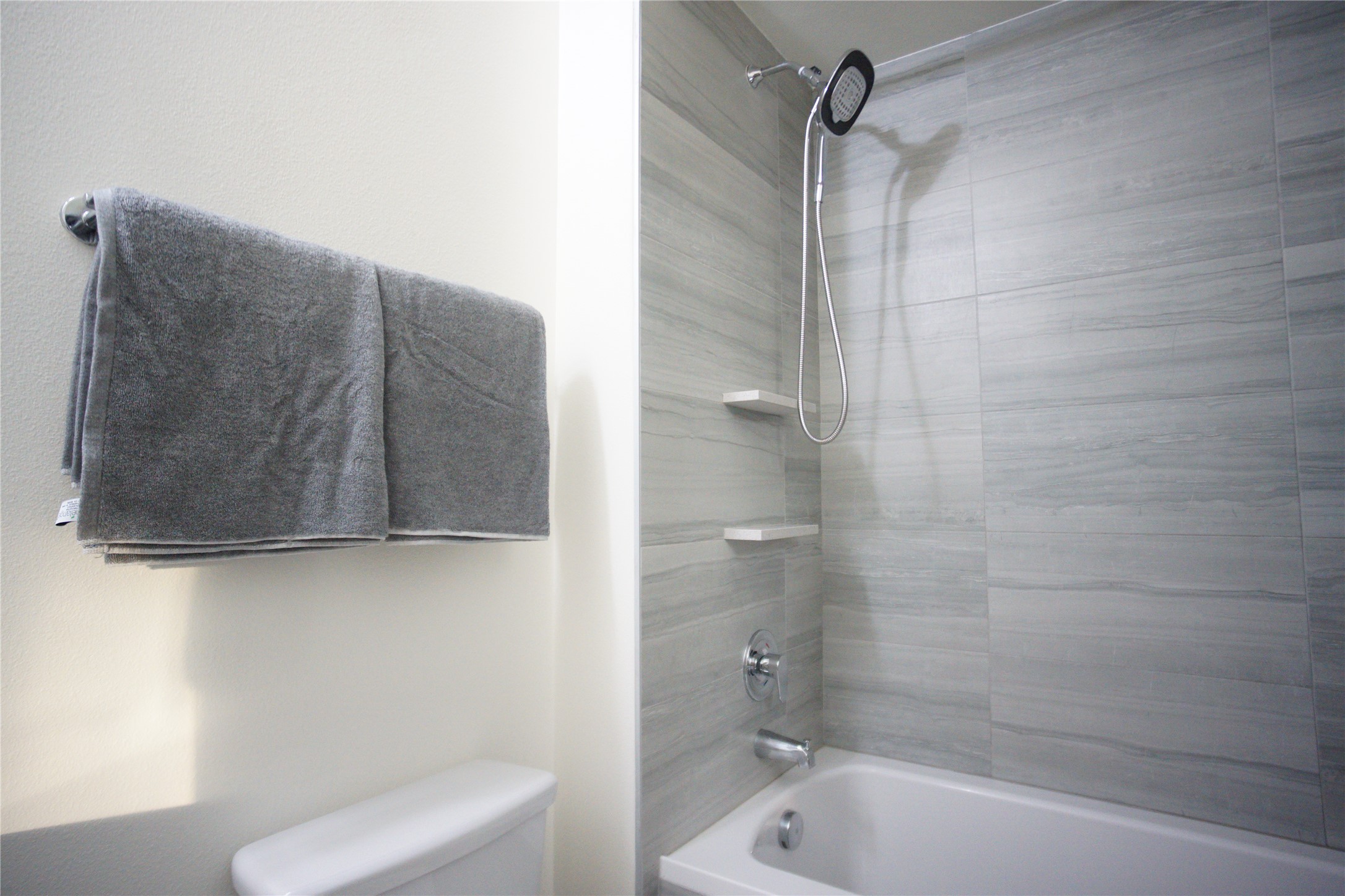 6444 Burnet Road, Unit 305 Austin, TX 78757 - Photo 12 of 15 Close-up of the tiled tub/shower with built-in shelving and a handheld showerhead.