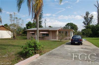 14 Arkansas Road Lehigh Acres, FL 33936 - Photo 1 of 7 a car parked in front of a house and a yard