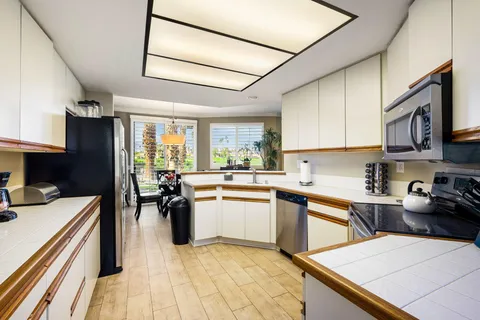 a kitchen with a refrigerator a stove top oven a sink dishwasher and white cabinets with wooden floor