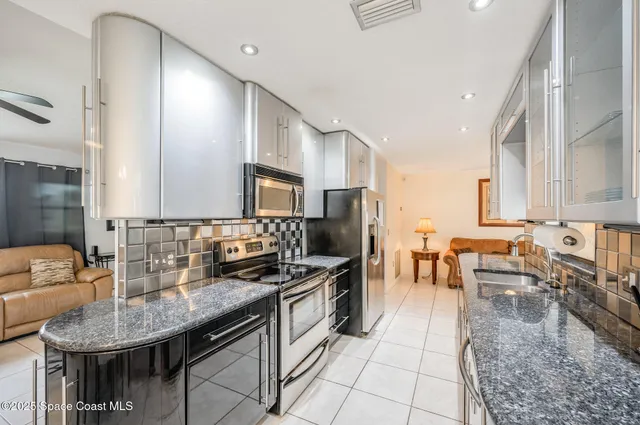 a kitchen with stainless steel appliances granite countertop a sink a stove counter space and cabinets
