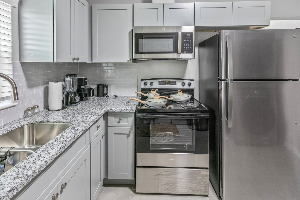 2824 Blodgett Street, Unit 2 Houston, TX 77004 - Photo 7 of 25 a kitchen with granite countertop a sink stove and refrigerator