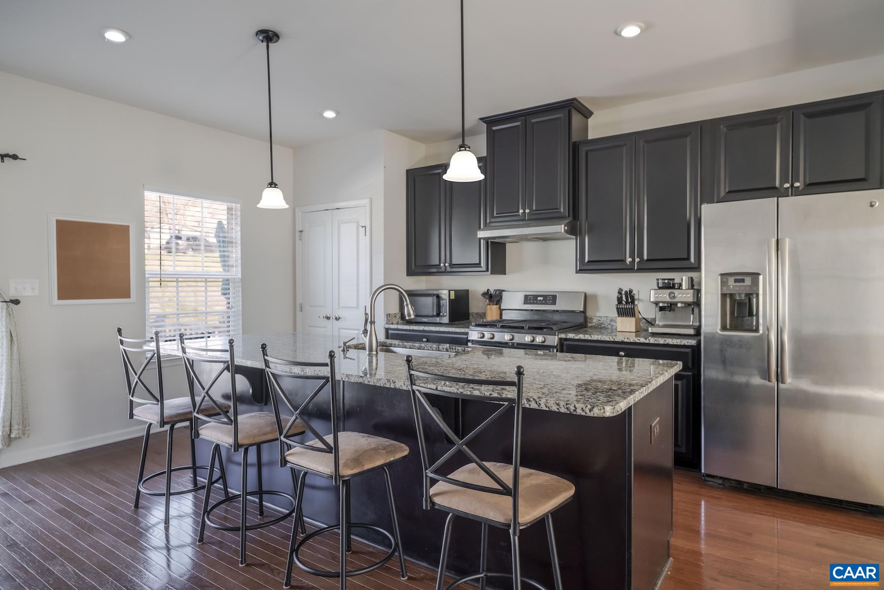 2052 Elm Tree Court Charlottesville, VA 22911 - Photo 7 of 26 a kitchen with stainless steel appliances granite countertop a stove a refrigerator a sink a dining table and chairs with wooden floor