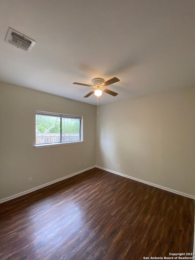 7214 Rimwood Street Live Oak, TX 78233 - Photo 19 of 24 a view of an empty room with wooden floor and a window