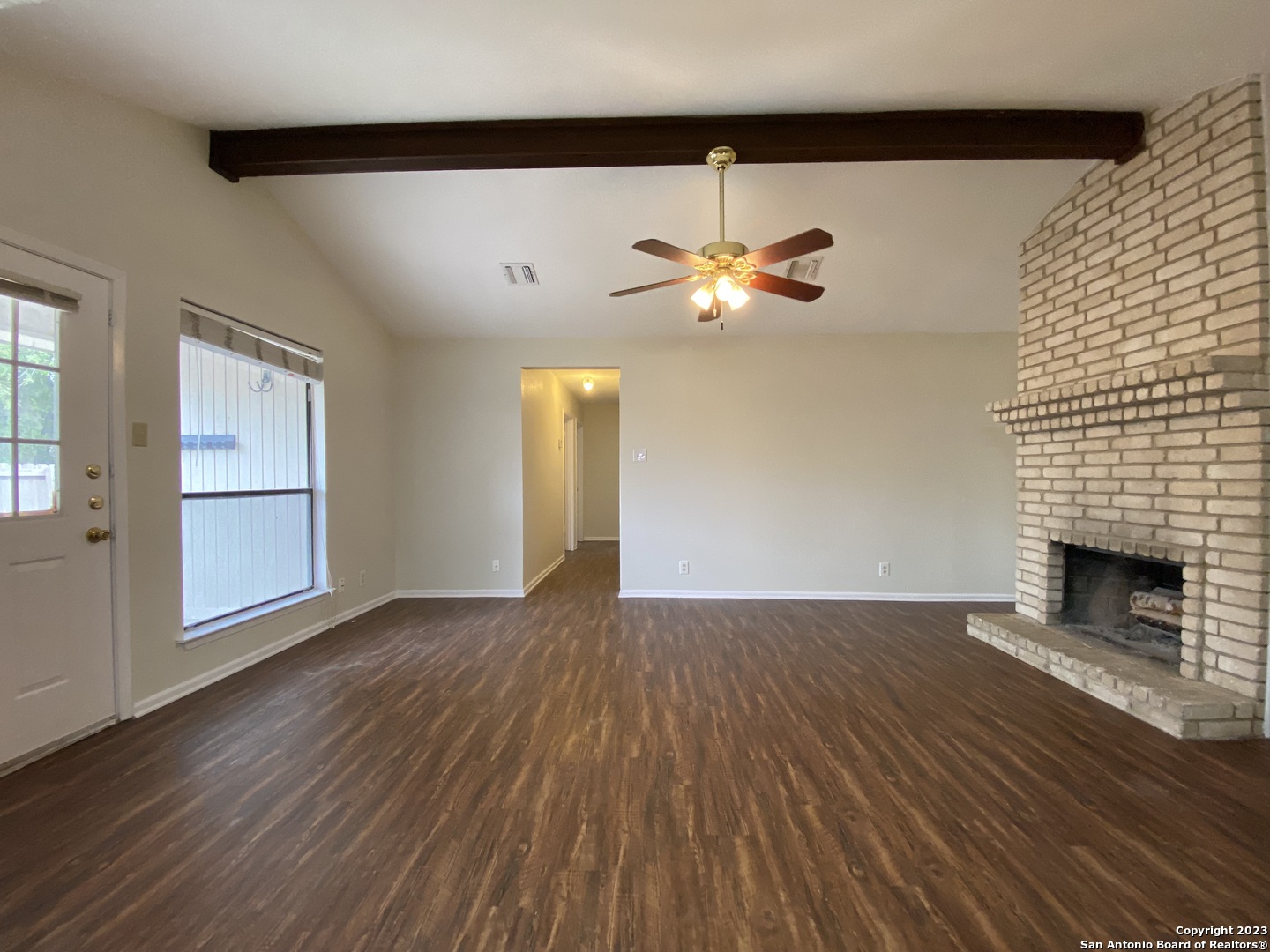 7214 Rimwood Street Live Oak, TX 78233 - Photo 4 of 24 an empty room with wooden floor fireplace and windows