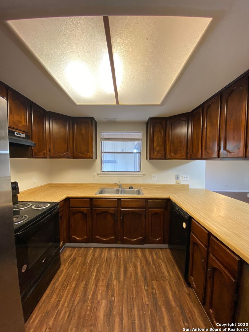 7214 Rimwood Street Live Oak, TX 78233 - Photo 9 of 24 a kitchen with stainless steel appliances granite countertop wooden cabinets a stove top oven a sink and dishwasher