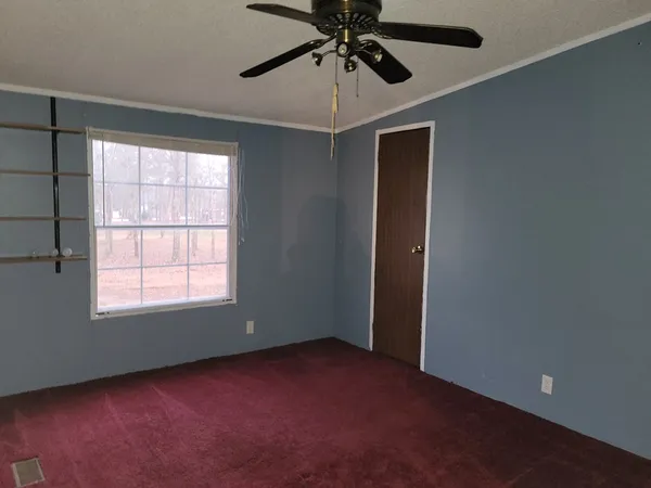 an empty room with a window and a fan