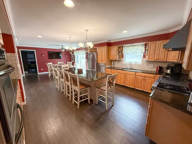 a kitchen with stainless steel appliances a dining table chairs stove refrigerator and cabinets