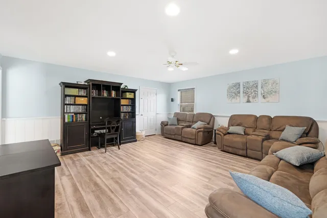 a living room with furniture a ceiling fan and a flat screen tv