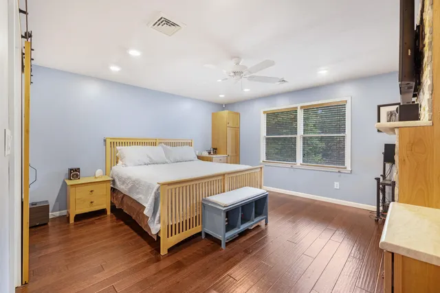 a spacious bedroom with a bed and wooden floor