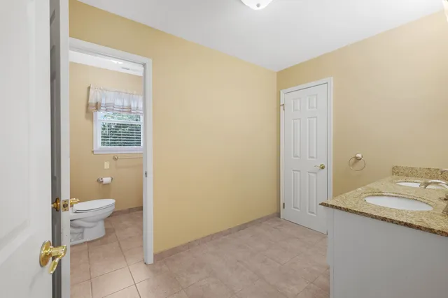 a bathroom with a granite countertop sink a toilet and a mirror