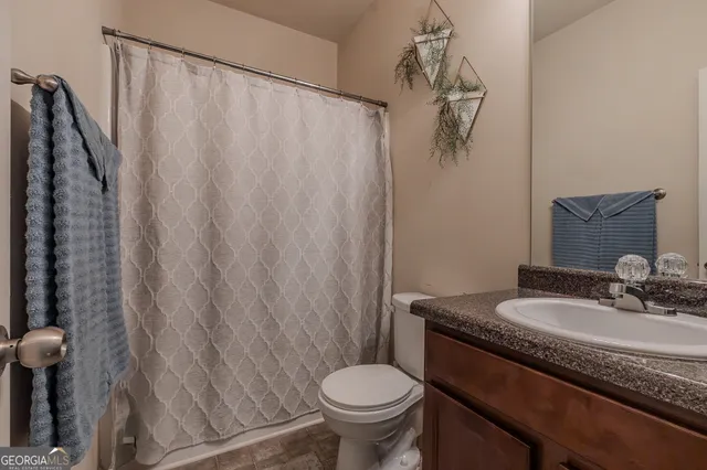 a bathroom with a granite countertop sink toilet and a mirror