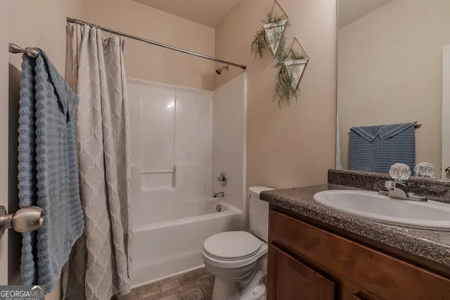 a bathroom with a granite countertop sink a toilet and shower
