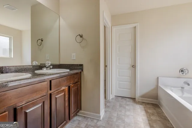 a bathroom with a granite countertop sink a mirror and a bathtub