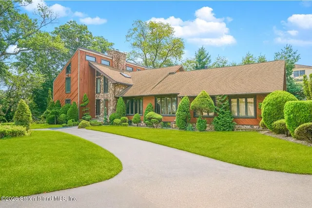 a view of a house with a big yard plants and large trees