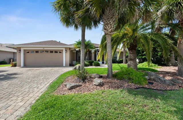 a front view of a house with a garden and palm trees