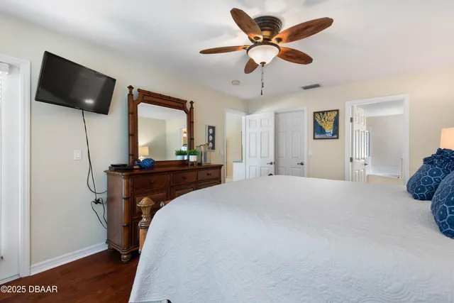 a bedroom with a bed and a flat tv screen on dresser