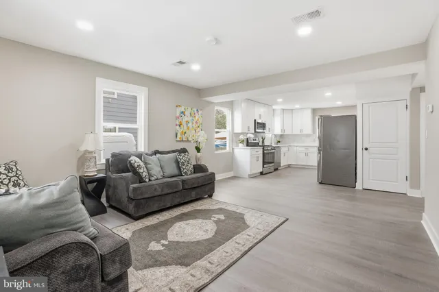 a living room with furniture and kitchen view with wooden floor