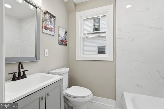 a bathroom with a toilet a sink a mirror and a window