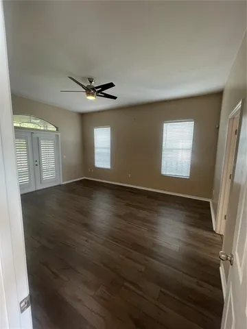 an empty room with wooden floor and windows
