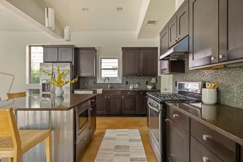 a kitchen with stainless steel appliances granite countertop sink stove top oven and cabinets