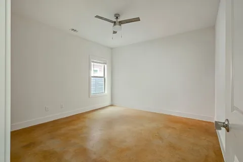an empty room with windows and fan