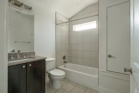 a bathroom with a granite countertop bathtub shower sink vanity and toilet