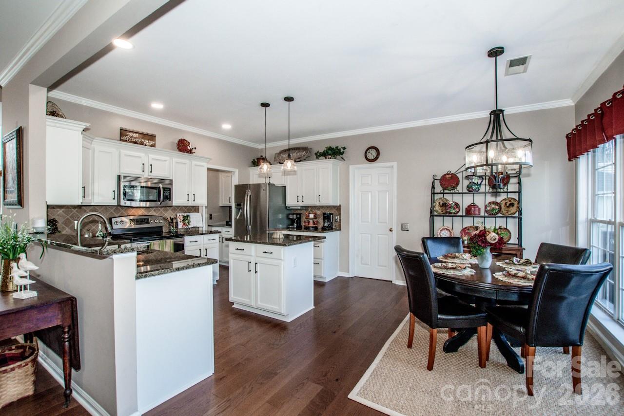 150 Coronilla Road Mooresville, NC 28117 - Photo 16 of 39 a kitchen with stainless steel appliances kitchen island granite countertop a table chairs and a refrigerator
