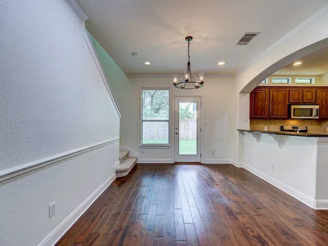 a view of a room with wooden floor a chandelier and window