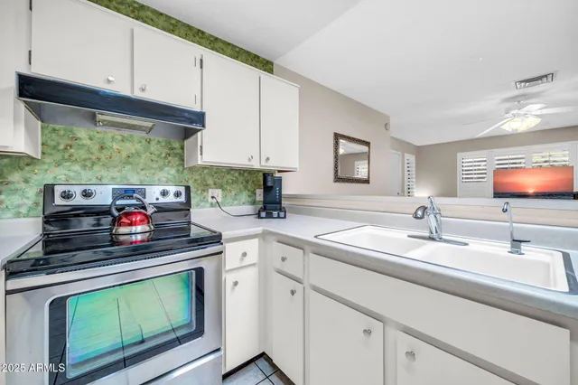 a kitchen with stainless steel appliances white cabinets and a stove top oven