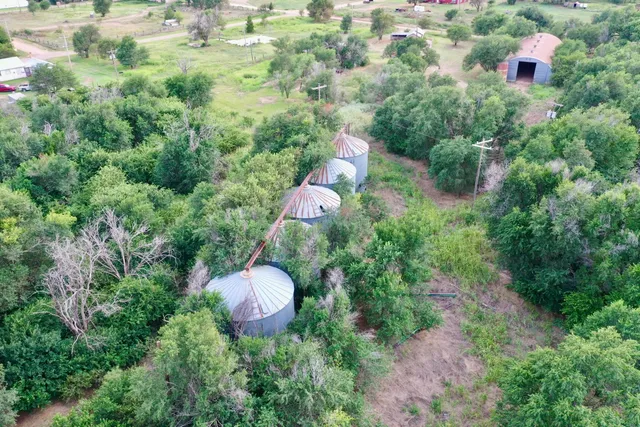 an aerial view of residential house with outdoor space and trees all around
