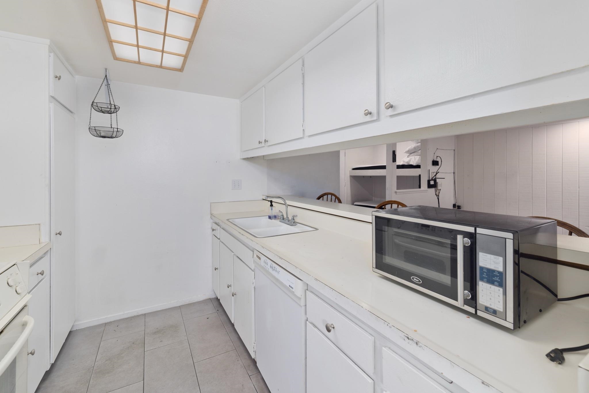 25 Lee Road, Unit 103 Mammoth Lakes, CA 93546 - Photo 13 of 29 White kitchen cabinetry with silver-tone hardware, a drop-in sink, and light-toned countertops